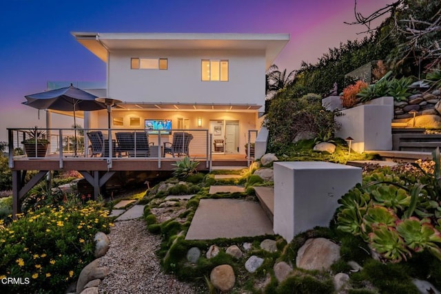 rear view of property with a deck and stucco siding