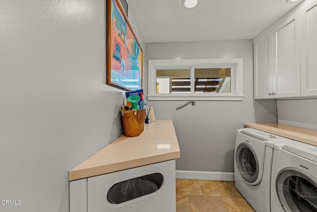 laundry area featuring baseboards, cabinet space, and washing machine and dryer