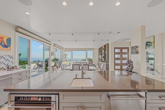 kitchen featuring recessed lighting, decorative backsplash, track lighting, stainless steel dishwasher, and open floor plan