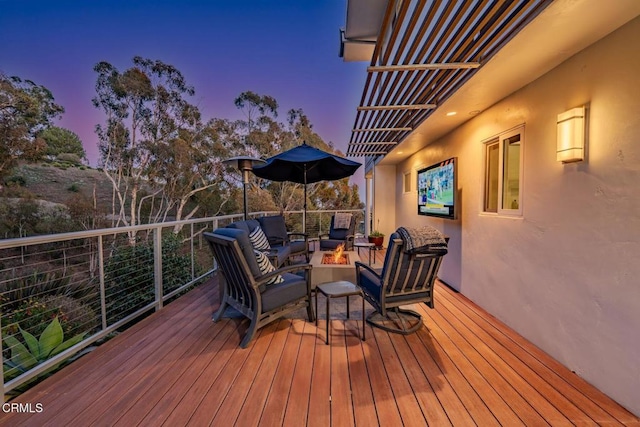 deck at dusk featuring an outdoor living space with a fire pit