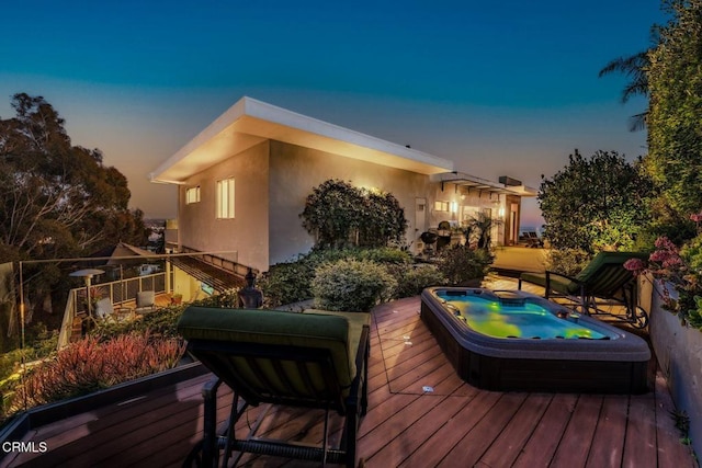 deck at dusk featuring hot tub deck surround