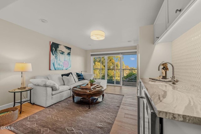 living area featuring baseboards, light wood finished floors, and beverage cooler