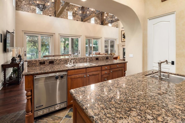 kitchen featuring dishwasher, a high ceiling, brown cabinetry, and a sink