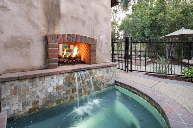 view of pool featuring fence and an outdoor brick fireplace