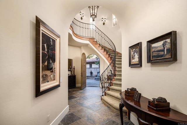 foyer entrance featuring stairs, stone tile floors, baseboards, and arched walkways