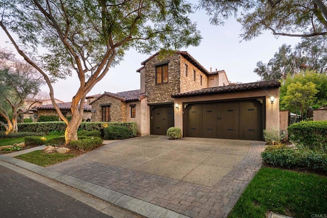 view of front of house with a tiled roof, stone siding, driveway, and stucco siding