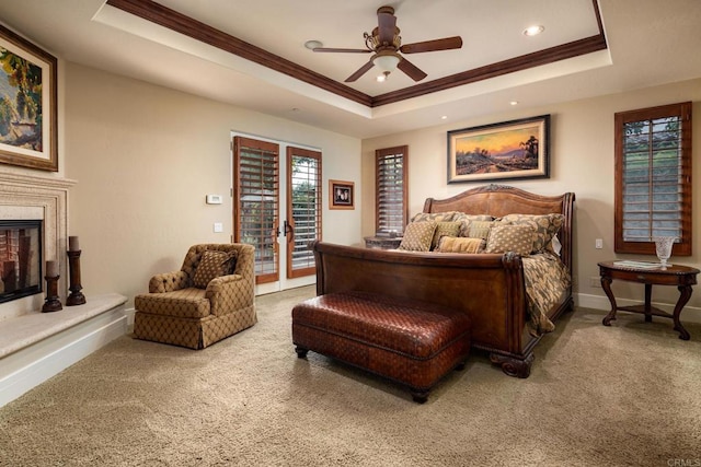 carpeted bedroom featuring a raised ceiling, a high end fireplace, crown molding, baseboards, and access to exterior