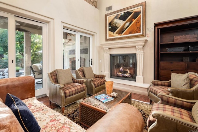 living room featuring visible vents, a glass covered fireplace, and wood finished floors