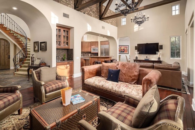 living room featuring visible vents, dark wood finished floors, stairway, an inviting chandelier, and arched walkways