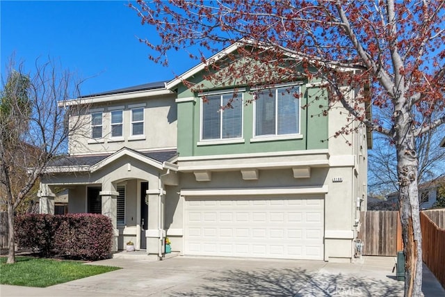 view of front of house with concrete driveway, fence, a garage, and stucco siding