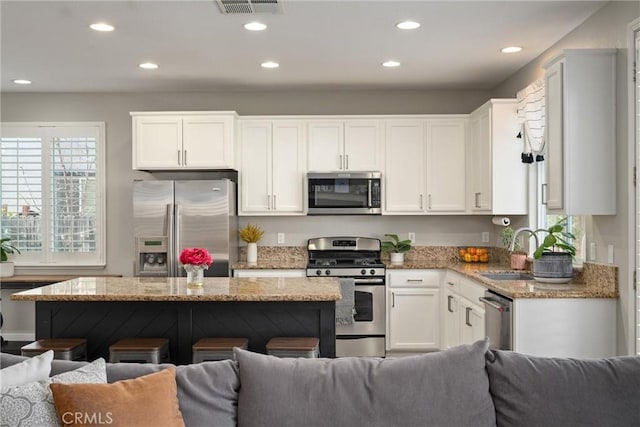 kitchen featuring white cabinetry, open floor plan, appliances with stainless steel finishes, and a sink