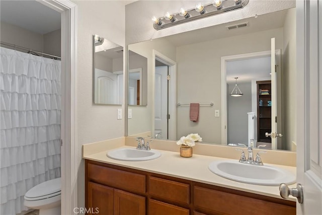 bathroom featuring double vanity, toilet, visible vents, and a sink