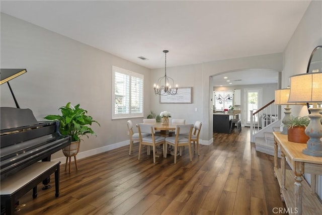 dining space with visible vents, stairway, arched walkways, a chandelier, and dark wood-style flooring