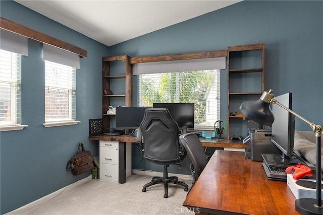 office area featuring vaulted ceiling, baseboards, and light carpet