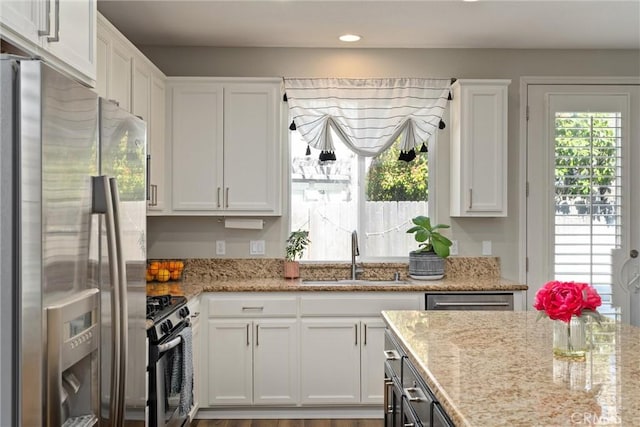 kitchen with light stone counters, recessed lighting, a sink, appliances with stainless steel finishes, and white cabinetry