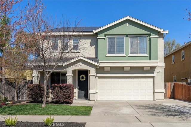 traditional-style house with stucco siding, an attached garage, concrete driveway, and fence