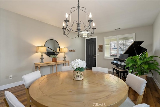 dining room featuring visible vents, a notable chandelier, wood finished floors, and baseboards