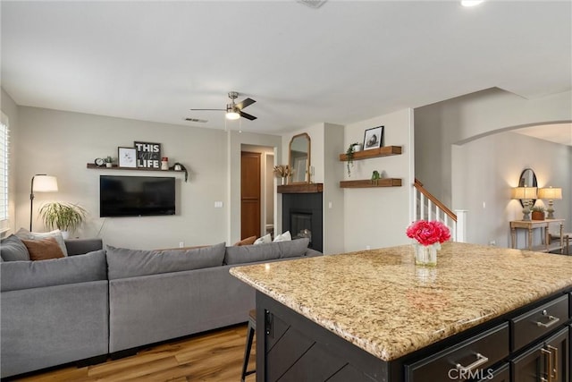 kitchen featuring arched walkways, open floor plan, light wood-style flooring, and ceiling fan