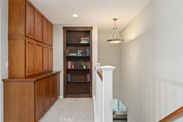 corridor featuring an upstairs landing and light colored carpet