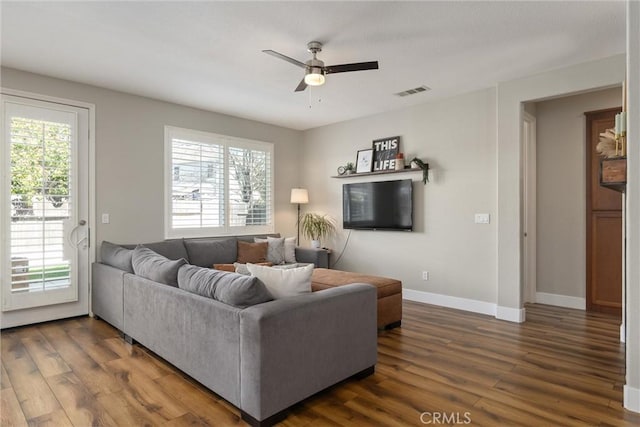 living area with a wealth of natural light, visible vents, and dark wood finished floors