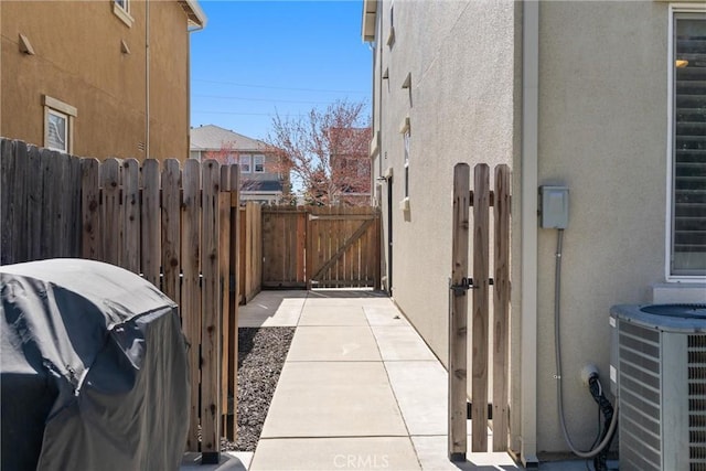 view of side of property featuring central air condition unit, fence, stucco siding, and a gate