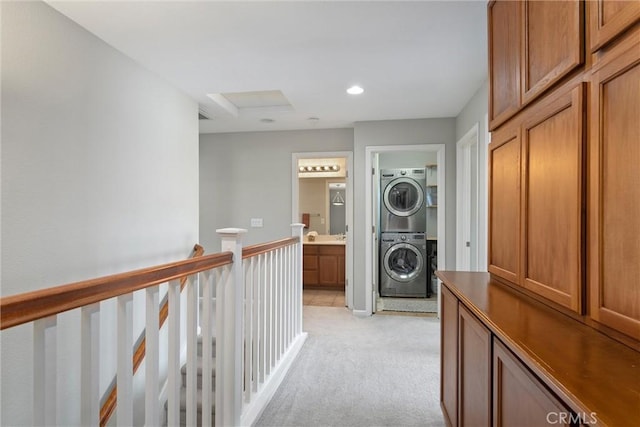 hallway featuring recessed lighting, light carpet, an upstairs landing, and stacked washer / dryer