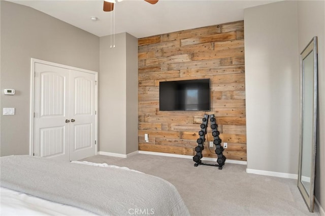 bedroom featuring baseboards, ceiling fan, wood walls, carpet flooring, and a closet