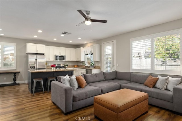 living area featuring a ceiling fan, visible vents, baseboards, recessed lighting, and dark wood-type flooring