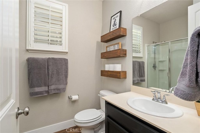 bathroom with baseboards, a shower stall, vanity, and toilet