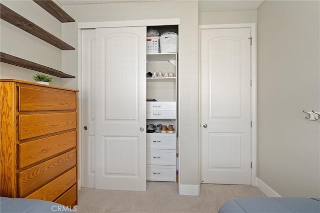 bedroom with a closet, light carpet, and baseboards