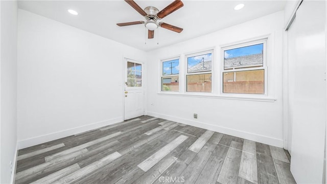 unfurnished room with a ceiling fan, recessed lighting, wood finished floors, and baseboards