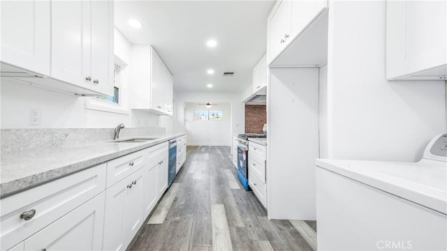 kitchen featuring washer / dryer, a sink, white cabinets, under cabinet range hood, and appliances with stainless steel finishes