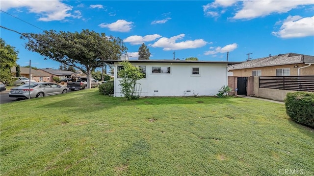 rear view of property with stucco siding, a yard, and fence