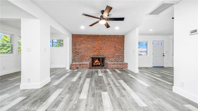 unfurnished living room featuring baseboards, wood finished floors, visible vents, and ceiling fan