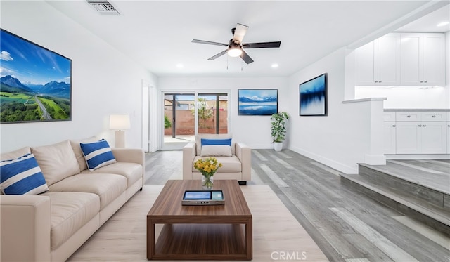 living room with visible vents, baseboards, ceiling fan, and light wood-style flooring