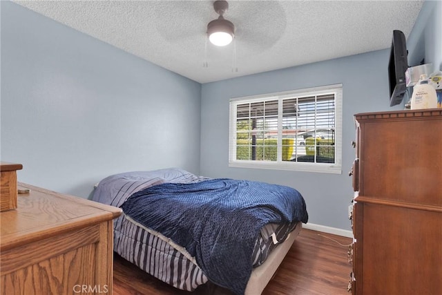 bedroom featuring dark wood finished floors, ceiling fan, a textured ceiling, and baseboards