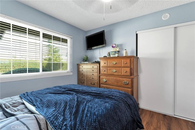 bedroom featuring a closet, a textured ceiling, a ceiling fan, and dark wood-style flooring