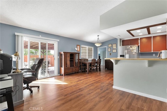 interior space with a textured ceiling, wood finished floors, and vaulted ceiling