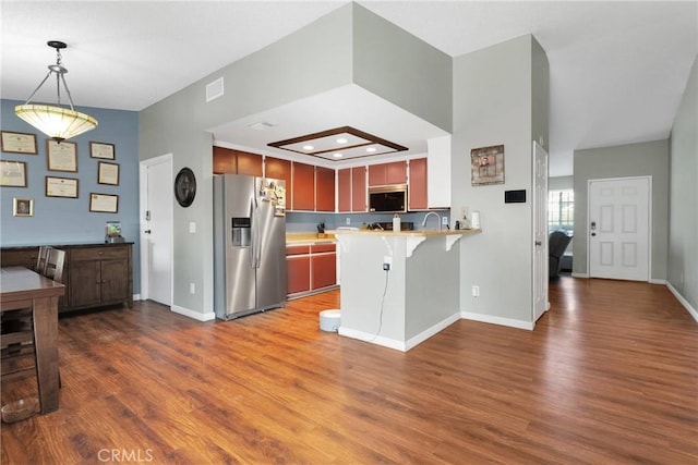 kitchen with wood finished floors, visible vents, a peninsula, stainless steel appliances, and light countertops