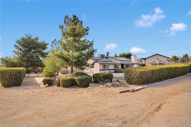 ranch-style home with solar panels and a chimney