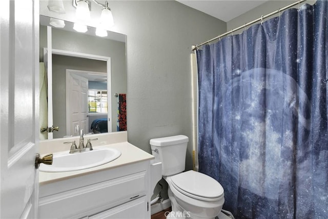 bathroom featuring curtained shower, toilet, vanity, and a textured wall