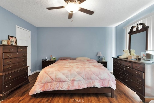 bedroom featuring dark wood-type flooring, a ceiling fan, baseboards, and a textured ceiling