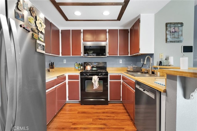 kitchen featuring light wood-style flooring, a sink, recessed lighting, appliances with stainless steel finishes, and light countertops