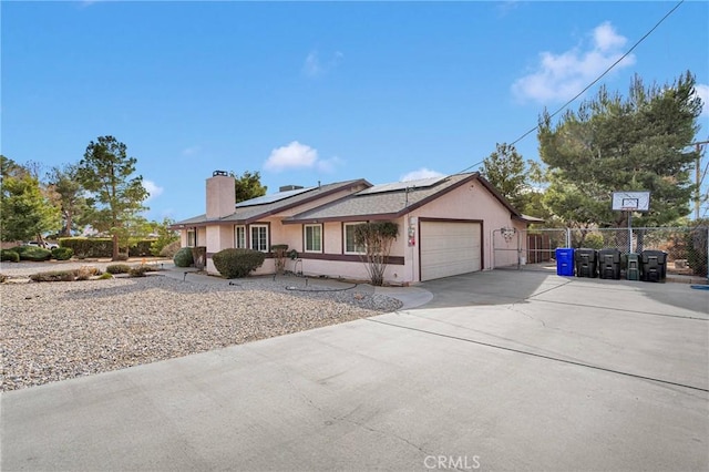 single story home with fence, driveway, stucco siding, a garage, and roof mounted solar panels