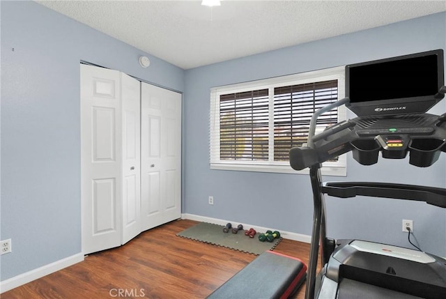 workout room with wood finished floors, baseboards, and a textured ceiling