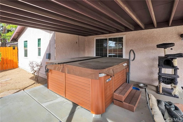 view of patio featuring a hot tub and fence