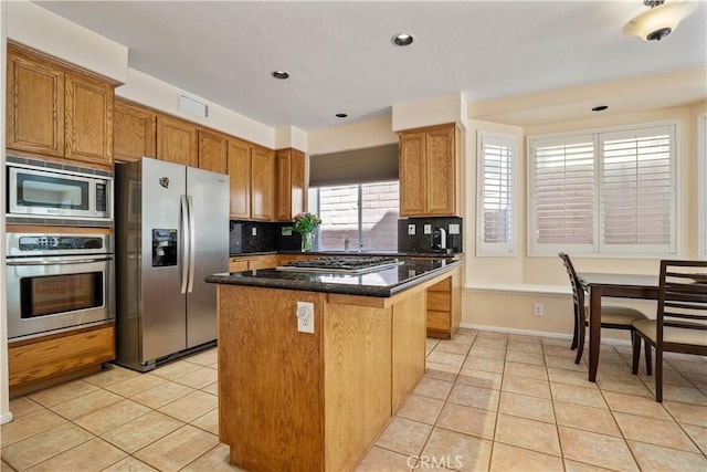 kitchen with light tile patterned floors, visible vents, a kitchen island, decorative backsplash, and appliances with stainless steel finishes