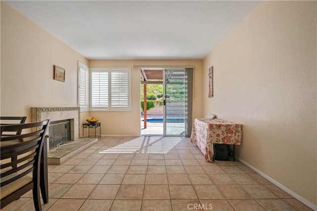 interior space with light tile patterned floors, baseboards, and a tiled fireplace