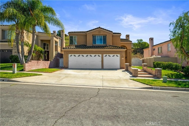 mediterranean / spanish house featuring a tile roof, an attached garage, driveway, and stucco siding