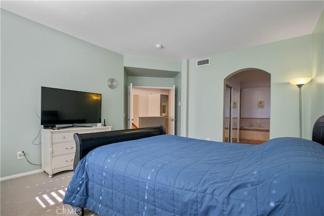 bedroom with arched walkways, visible vents, baseboards, and carpet